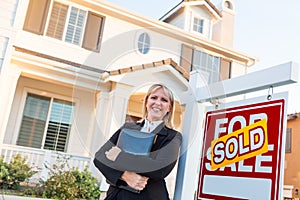 Female Real Estate Agent in Front of Sold For Sale Sign and Beautiful House