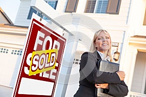 Female Real Estate Agent in Front of Sold For Sale Sign and Beautiful House