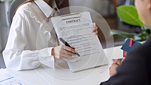 A female real estate agent hands a rental contract to a new tenant