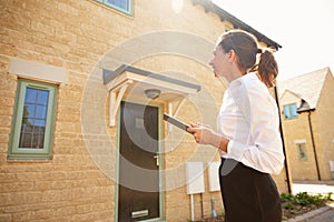 Female real estate agent looking at a house exterior