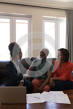 Female real estate agent shaking hands with senior man in living room