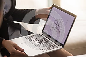Female real estate agent showing house plan on laptop screen