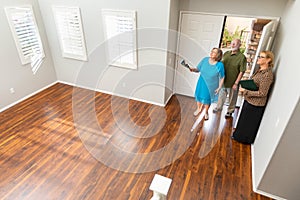 Female Real Estate Agent Showing Senior Adult Couple A New Home