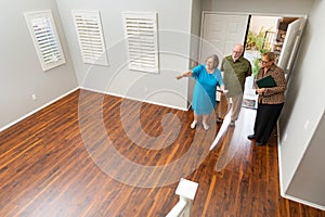 Female Real Estate Agent Showing Senior Adult Couple A New Home