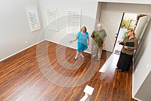 Female Real Estate Agent Showing Senior Adult Couple A New Home