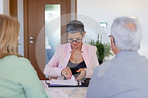 Female real estate agent signing documents with customers