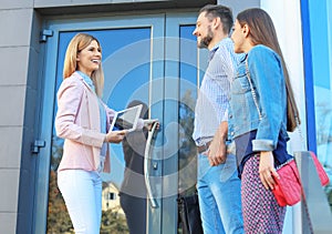 Female real estate agent welcoming couple to show hous