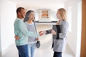 Female Realtor Shaking Hands With Couple Interested In Buying House photo