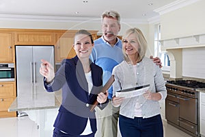 Female Realtor Showing Mature Couple Around House