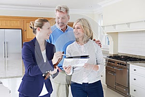 Female Realtor Showing Mature Couple Around House For Sale