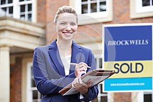 Portrait Of Female Realtor Standing Outside Residential Property photo