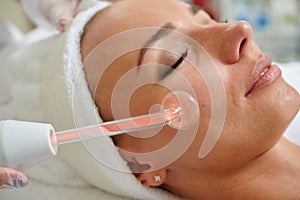 Female receiving galvanic treatment in spa cosmetologist professional services