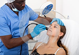 Female receiving hardware facial mesotherapy at cosmetology clinic
