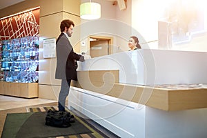 Female receptionist giving information to guest upon arrival at hotel.