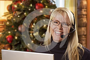 Female Receptionist Using Laptop Wearing Phone Headset Near Christmas Tree