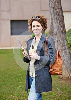 Female redhead student carrying notebook and coffee to go