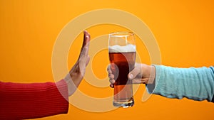 Female rejecting beer glass showing stop gesture, bad habit refusal, health care