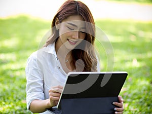 Female relaxes in a park and entertains herself with a tablet