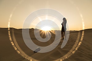 Female relaxing on the sand dune, admiring the oasis town of Huacachina, Ica, Peru.The sunset desert view