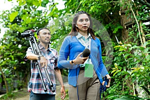 a female reporter and the cameraman walking through the village