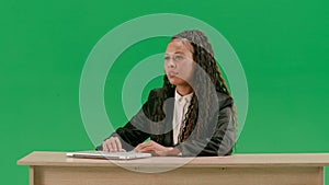 Female reporter at the desk isolated on chroma key green screen background. African american woman tv news host sitting