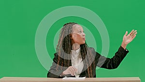 Female reporter at the desk isolated on chroma key green screen background. African american woman tv news host sitting