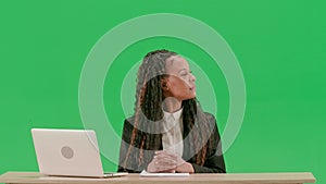 Female reporter at the desk isolated on chroma key green screen background. African american woman tv news host sitting