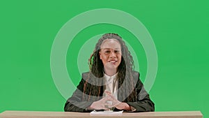 Female reporter at the desk isolated on chroma key green screen background. African american woman tv news host sitting