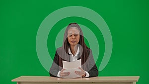 Female reporter isolated on chroma key green screen background. African American woman news host in suit reading