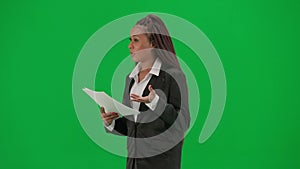 Female reporter isolated on chroma key green screen background. African American woman news host in suit reads paper