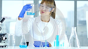 Female research scientist looking at solution in beaker in laboratory, reacti