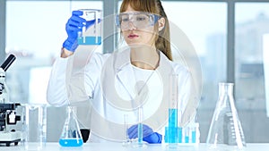 Female Research Scientist Looking at Solution in Beaker in Laboratory, Reaction