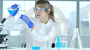 Female research scientist pouring chemical in beaker for reaction in laborato