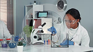 Female research scientist in safety glasses providing experiment with mouse and then showing her amazement