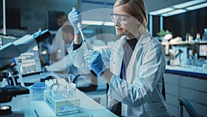 Female Research Scientist Uses Micropipette to Mix Liquids in a Sample Test Tube in a Modern Labor