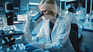Female Research Scientist is Wearing Glasses and Looking Under the Microscope to Make Analysis of