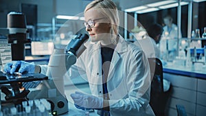Female Research Scientist is Wearing Glasses and Using Modern Microscope to Make Analysis of New B