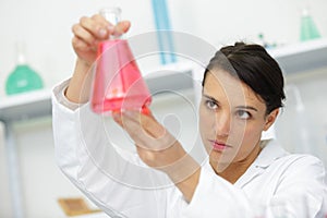 female researcher holding flask with red liquid photo