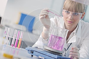 Female researcher holding up a test tube in lab