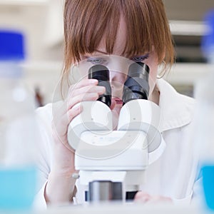 Female researcher using a microscope in a lab