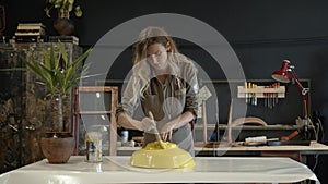 A female restorer painting a yellow detail in workshop