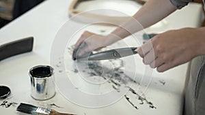 A female restorer polishing a black wooden detail