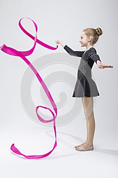 Female Rhythmic Gymnast In Professional Competitive Black Sparkling Starry Suit Doing Artistic Ribbon Spirals Exercises