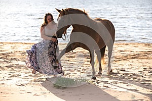 Female rider galloping along a beach on a brown horse.