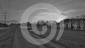 Female rider on horse in sunset far away in black and white