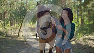 Female rider with purebred horse strolling in wood