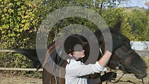 Female rider in riding clothes and helmet stroking her horse after ride