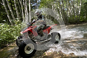 Female riding ATV through creek