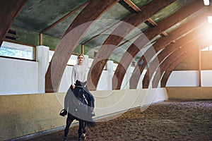 Female riding horse in indoor riding hall