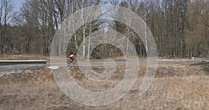 Female on road bike, portrait. Woman standing with bicycle in forest on empty road. Cyclist athlete in helmet preparing for cycleF